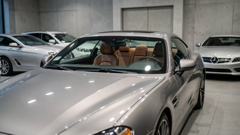 Berline coupé d’occasion au style premium dans un showroom urbain, peinture métallisée et intérieur en cuir visibles, éclairage doux et ambiance calme.